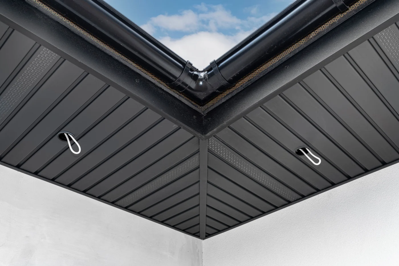 Residential Soffit Services In Colorado Springs A close-up of some dark metal soffit in a corner of a residential roof with special holes and strips with ventilation.