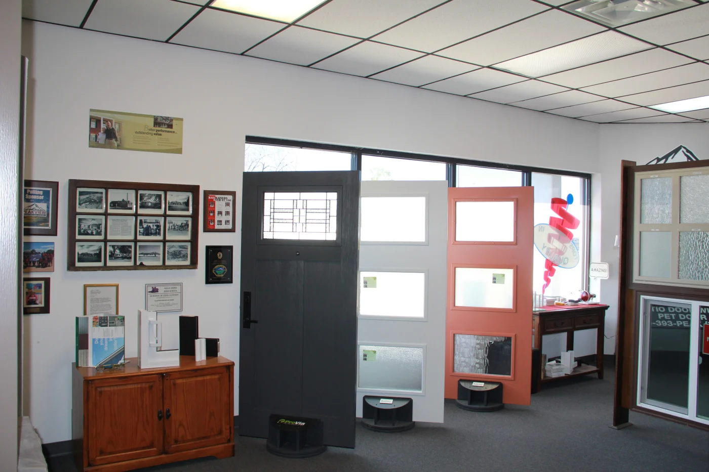A section of the Peakview Windows, Siding & Stucco showroom in Colorado Springs with full-size ProVia swing entry doors with different kinds of glass sitting in front of windows.