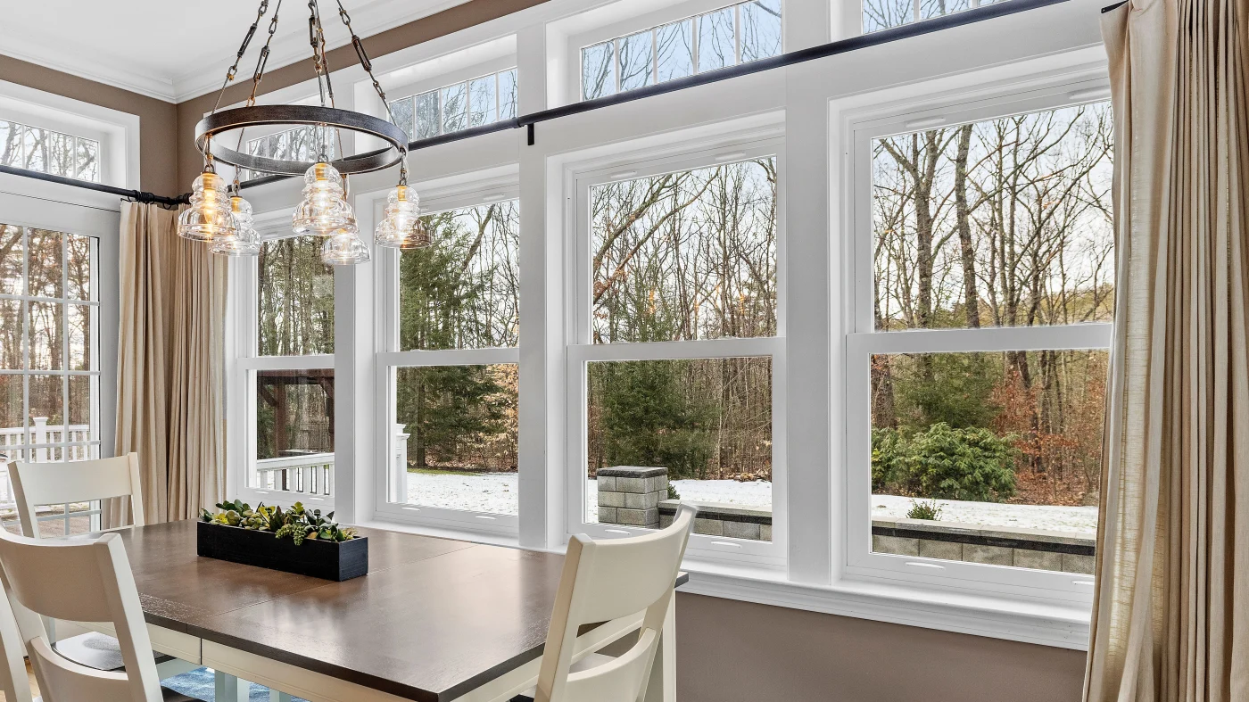 A dining room with a large wall of windows overlooking the trees
