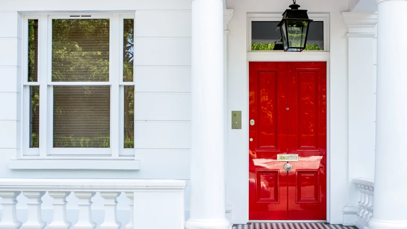 A home with white siding and a vibrant red entry door