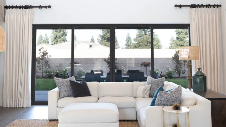 A white sofa seated in front of a sliding patio door with black trim.