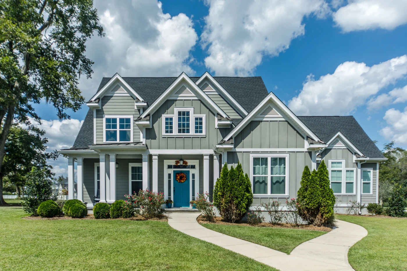 A large home with green fiber cement siding and white trim