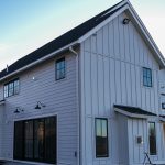 A large home with white fiber cement siding and black windows