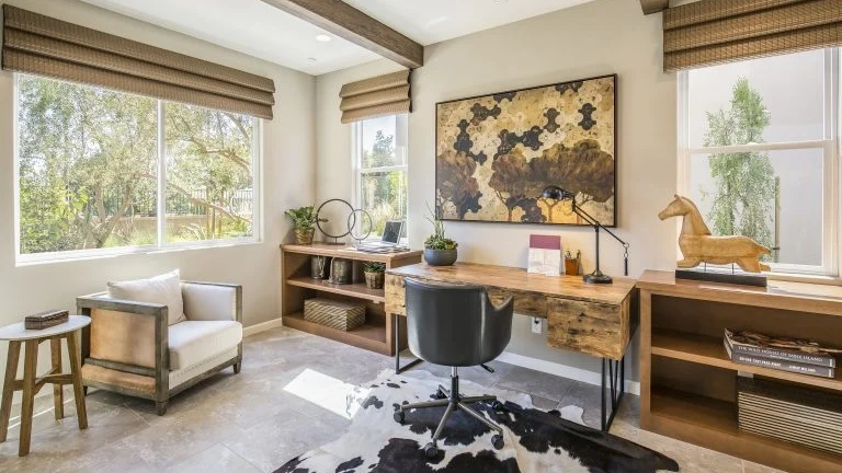 A home office with a large slider window on the left wall and windows framing the desk on the far wall