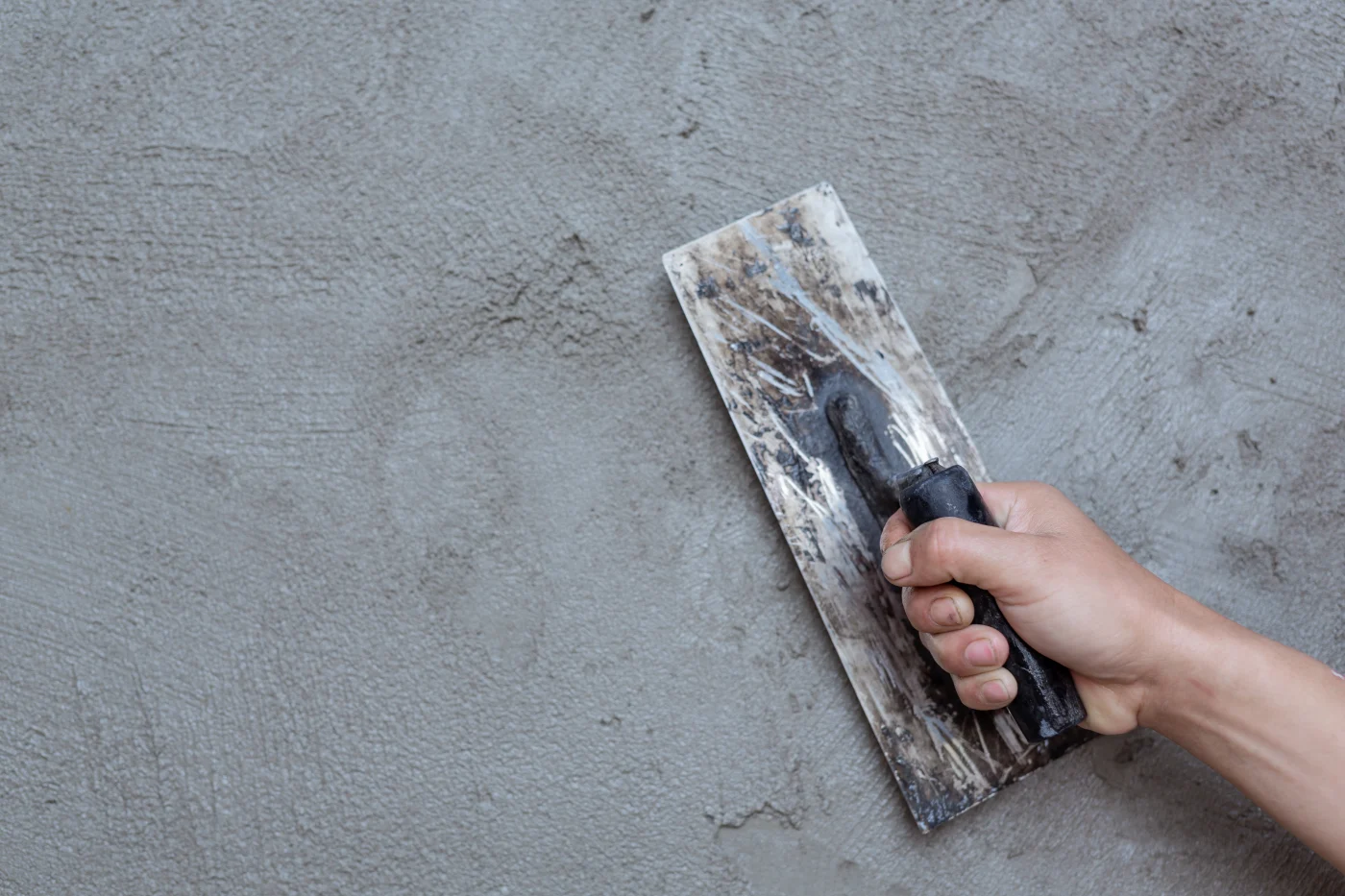 A worker's hand carefully puts the finishing touches on stucco.