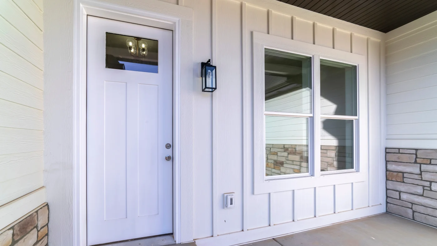 An entryway with a white door, white siding, and white windows