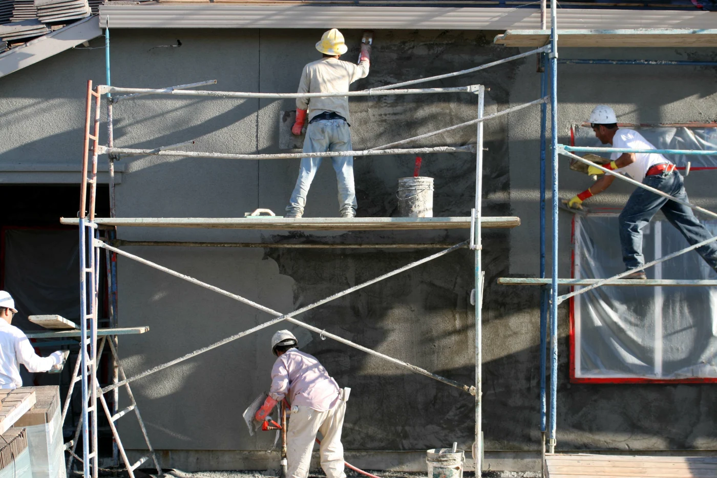 Contractors apply stucco to a home's exterior.