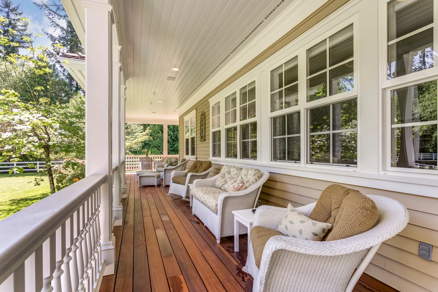 A wrap-around porch with wicker furniture and several double-hung windows.