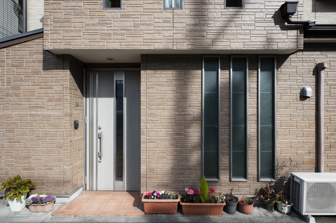 A large home with a facade of rectangular beige stone.