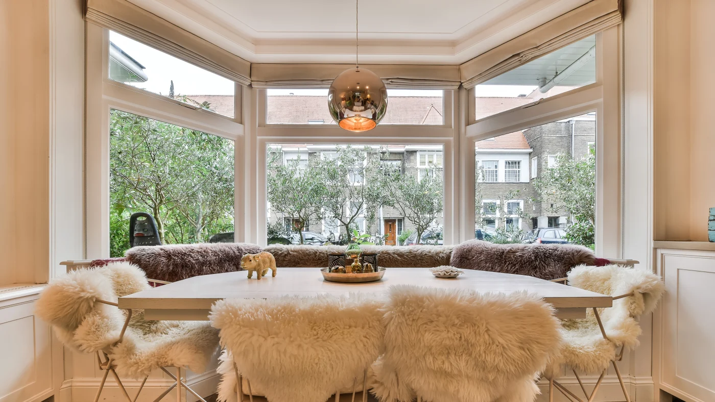 A dining room with large picture windows overlooking the street