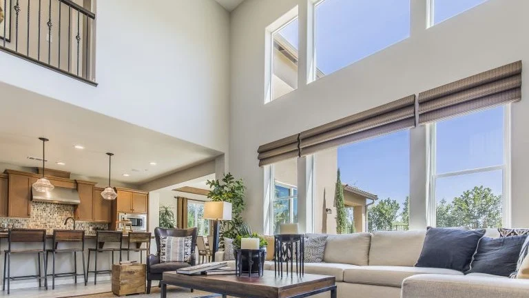A living room with a high ceiling and a wall of windows.