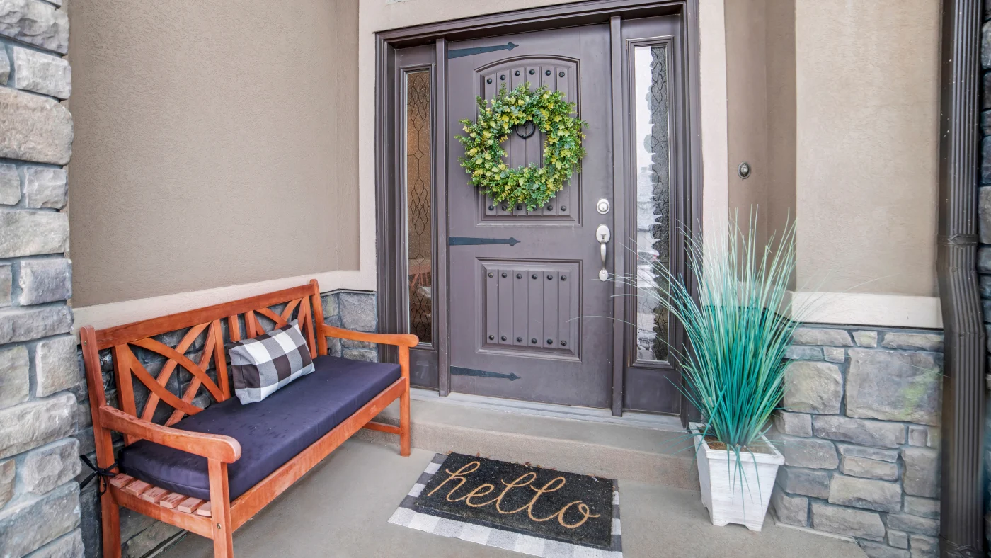 A gray door with a wreath and sidelights in a home with a stucco exterior.