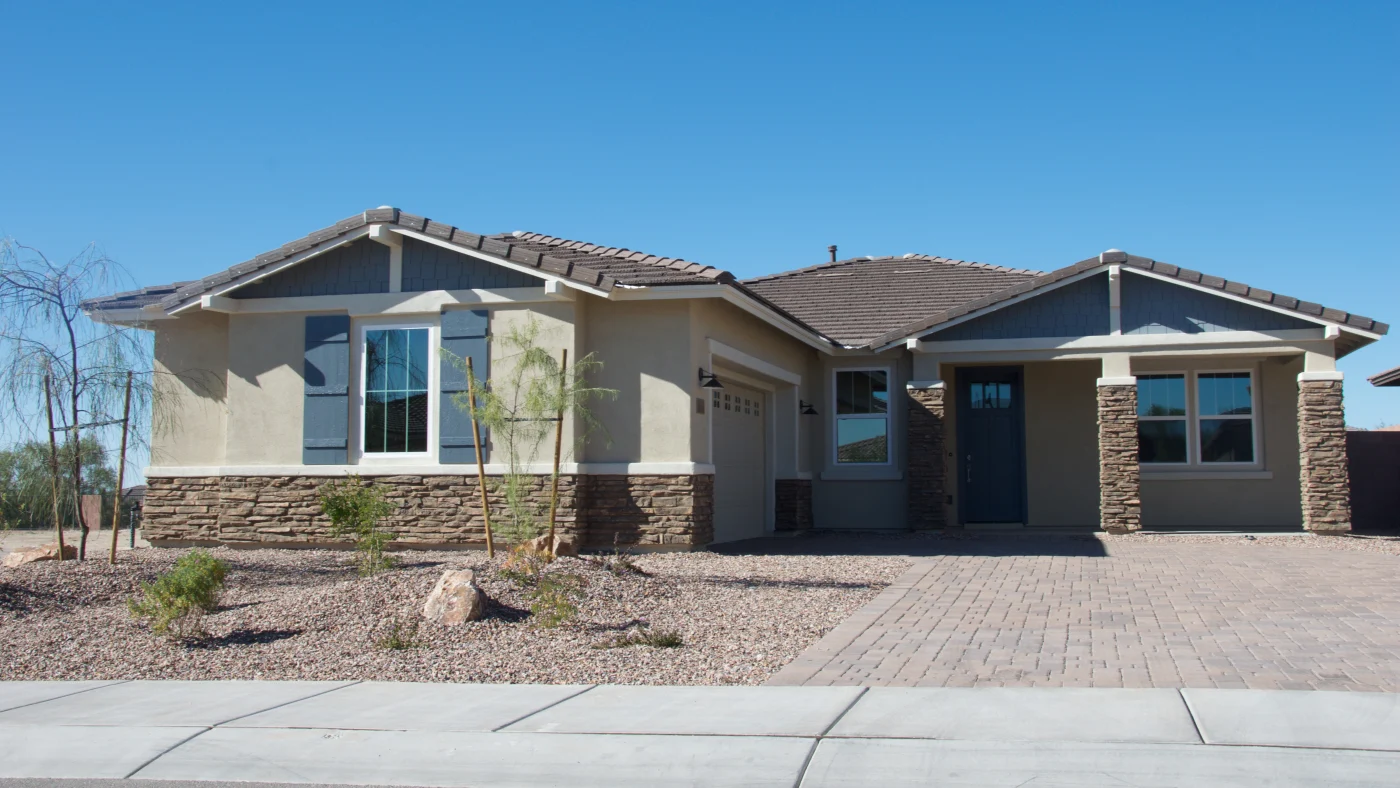 A home with tan stucco, white trim, and stone accents.