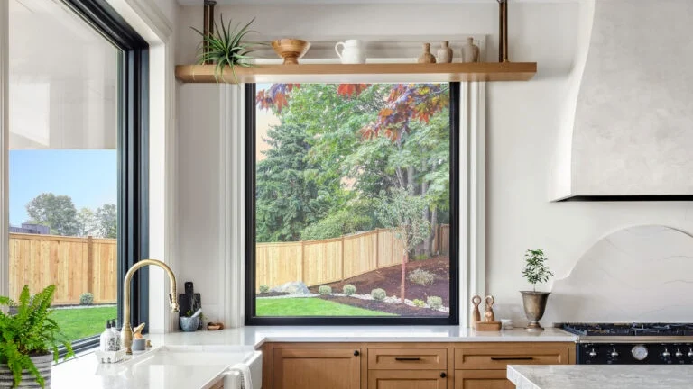 A kitchen with black picture windows over the sink and counter