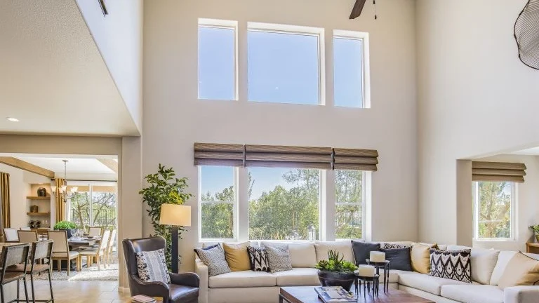 A living room with a high ceiling and a wall with two rows of windows