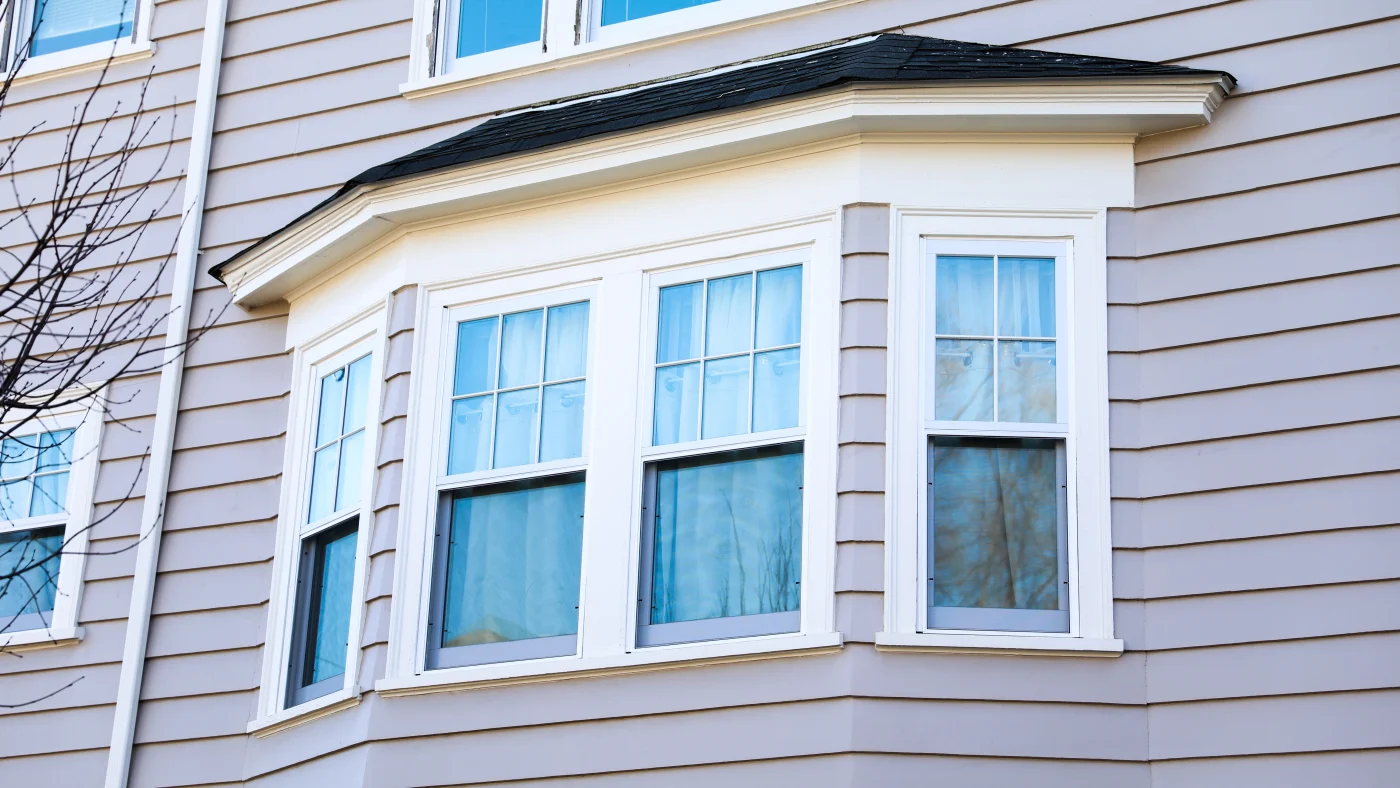 The exterior of a home with gray siding and white windows