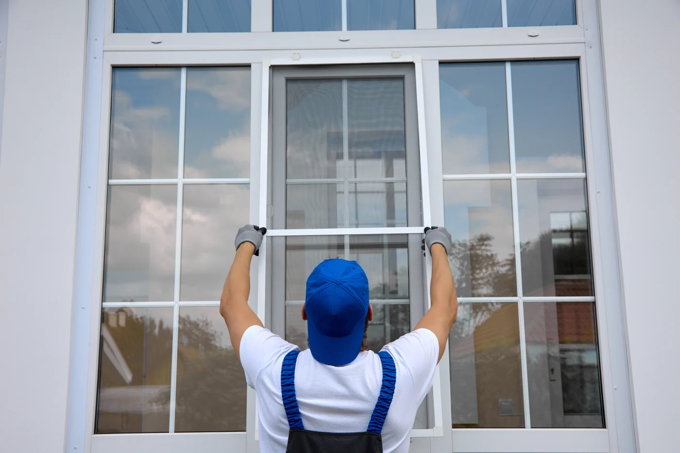 A window installer completes an installation by hanging a screen.