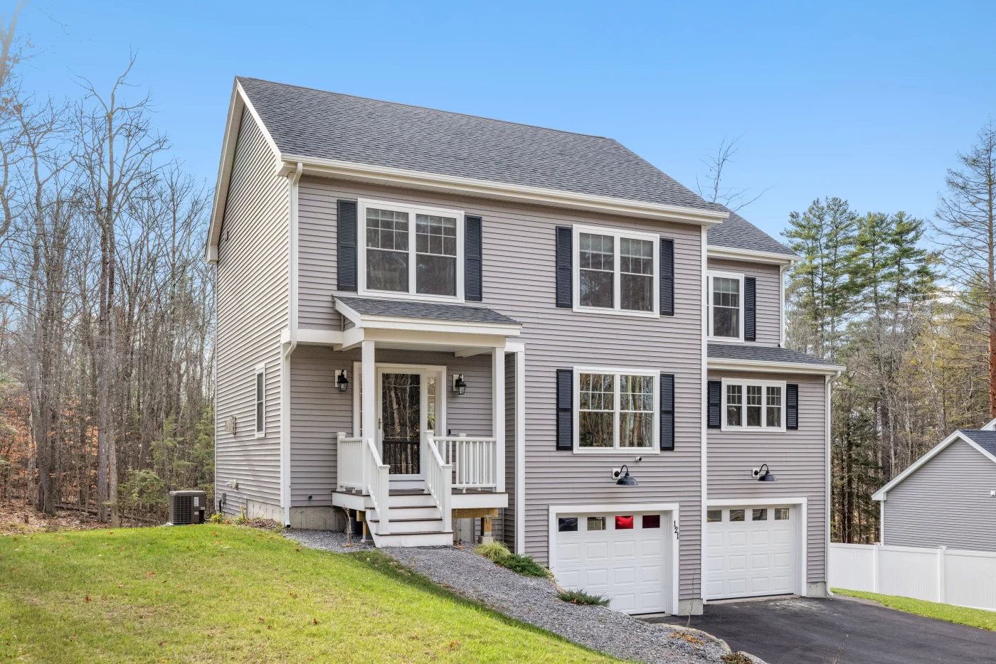 Large, two-story house with trees in the background and gray siding