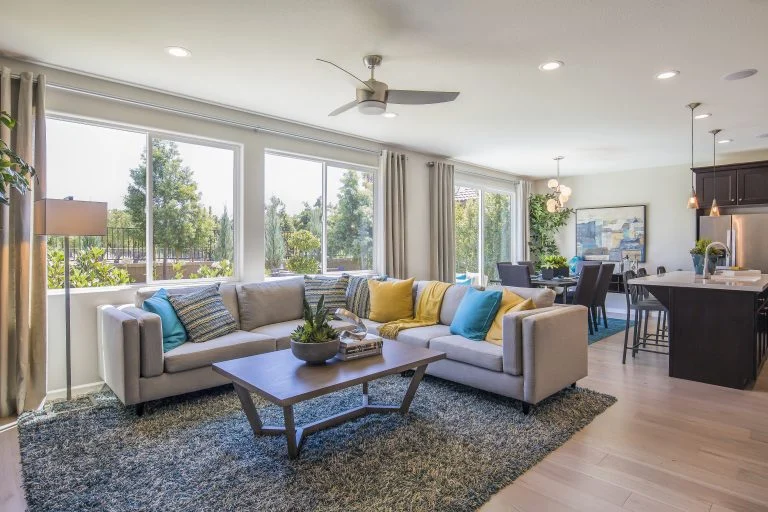 A large sitting room with a sectional and wall-to-wall windows.