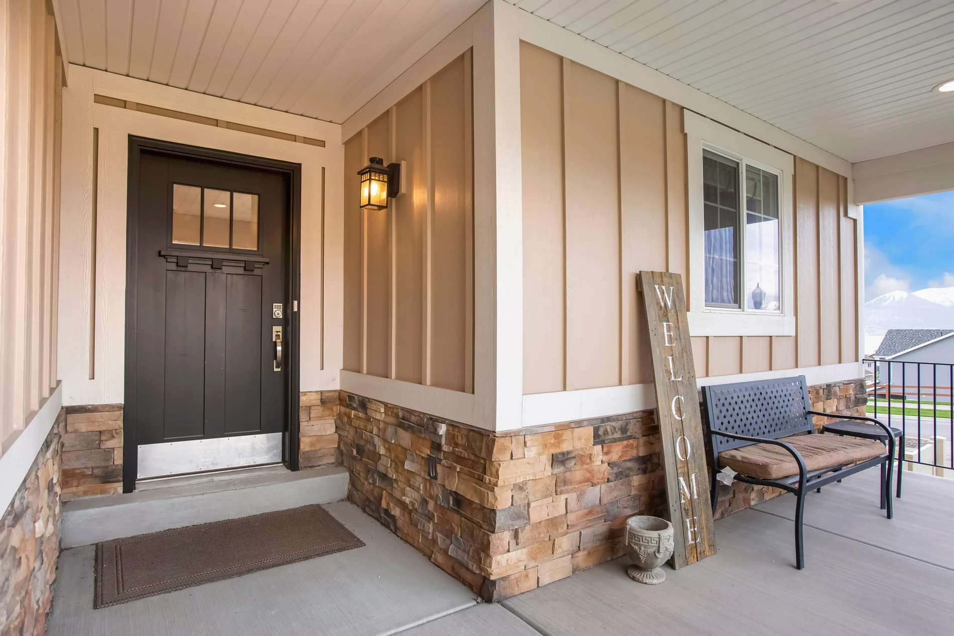 A dark brown entry door with a metal kickplate in a home with board and batten siding.