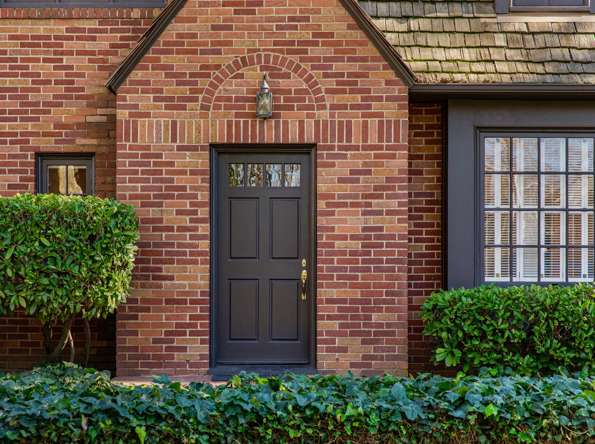 A brick home with a deep brown entry door.