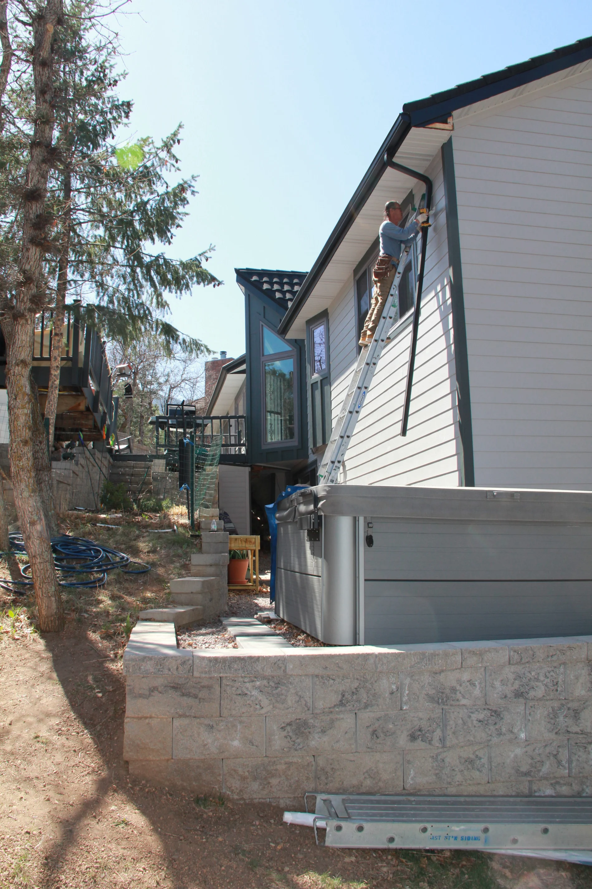 A contractor working for Peakview Windows installing white siding.