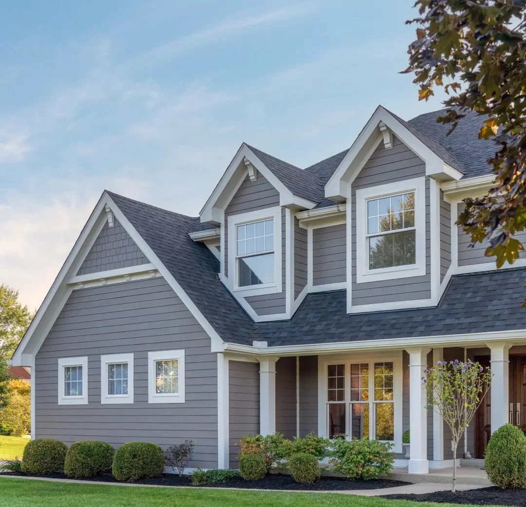Front of a two-story home with gray siding, white trim, and a yellow entry door.