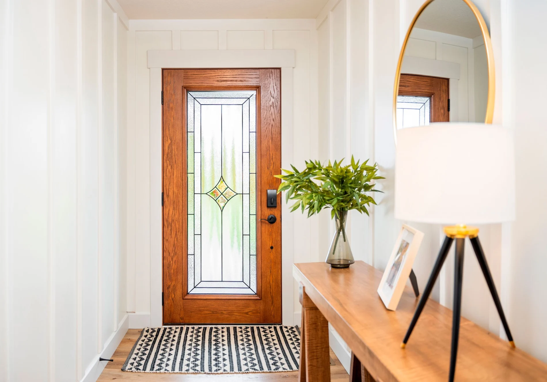 An interior view showcases a premium wood-grain entry door with an intricate decorative glass insert, providing a warm and inviting focal point for this modern Black Forest home's entryway.