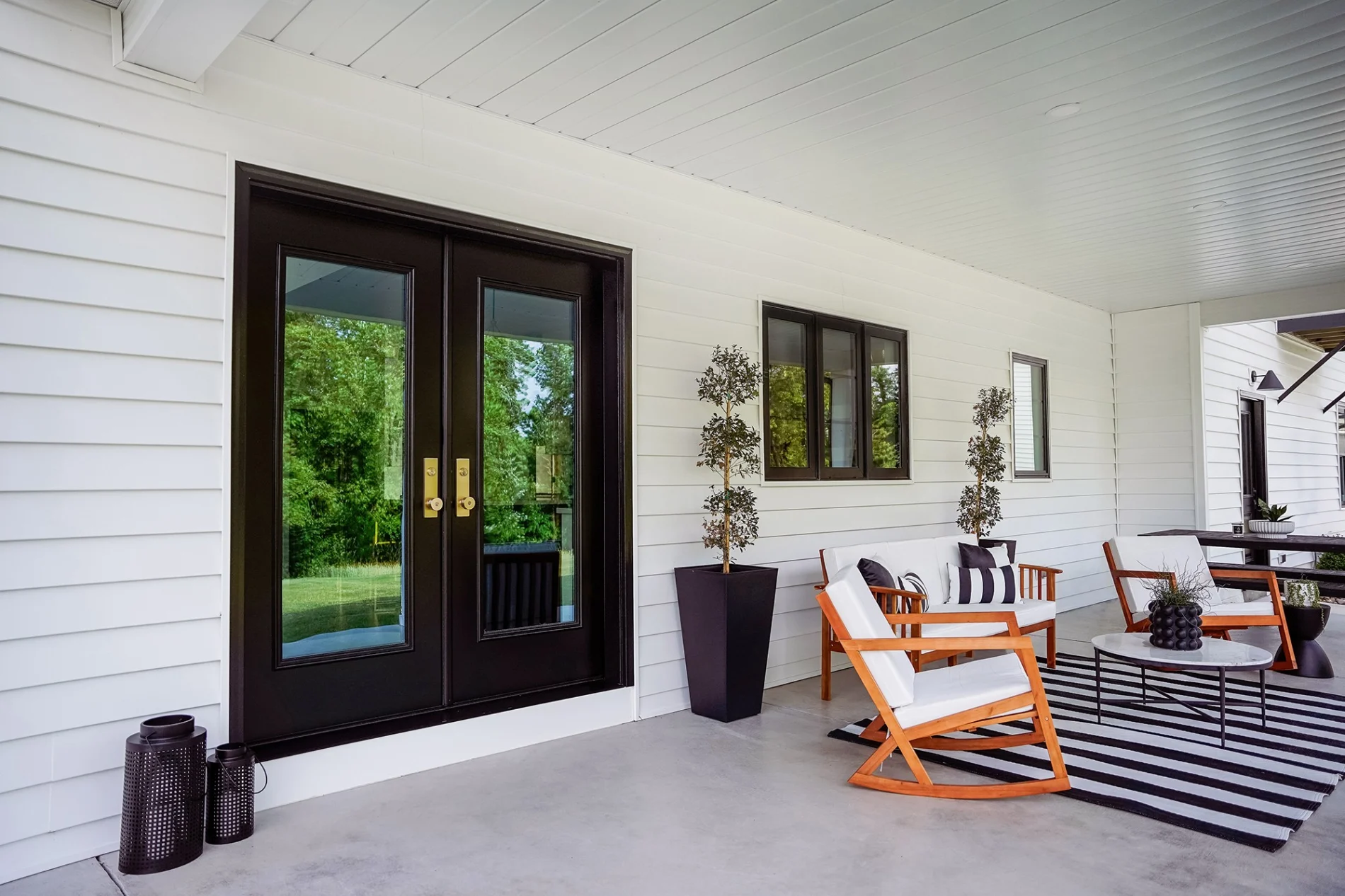 Expertly installed black-framed French doors create a stunning focal point for this Canon City porch, seamlessly connecting the elegant outdoor living space with the home's interior.