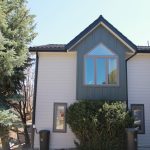 A beautiful residential building features a modern combination of light horizontal boards and a dark green vertical board and batten peak completed by a professional siding contractor.