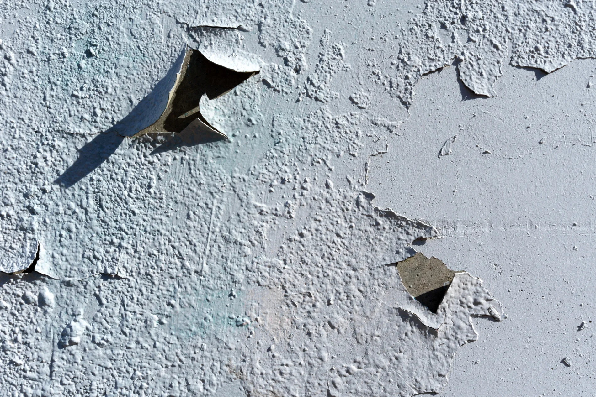 Design On Cement And Concrete Texture For Drawing And Background. A close-up view of peeling and deteriorating teal stucco on the side of a house.