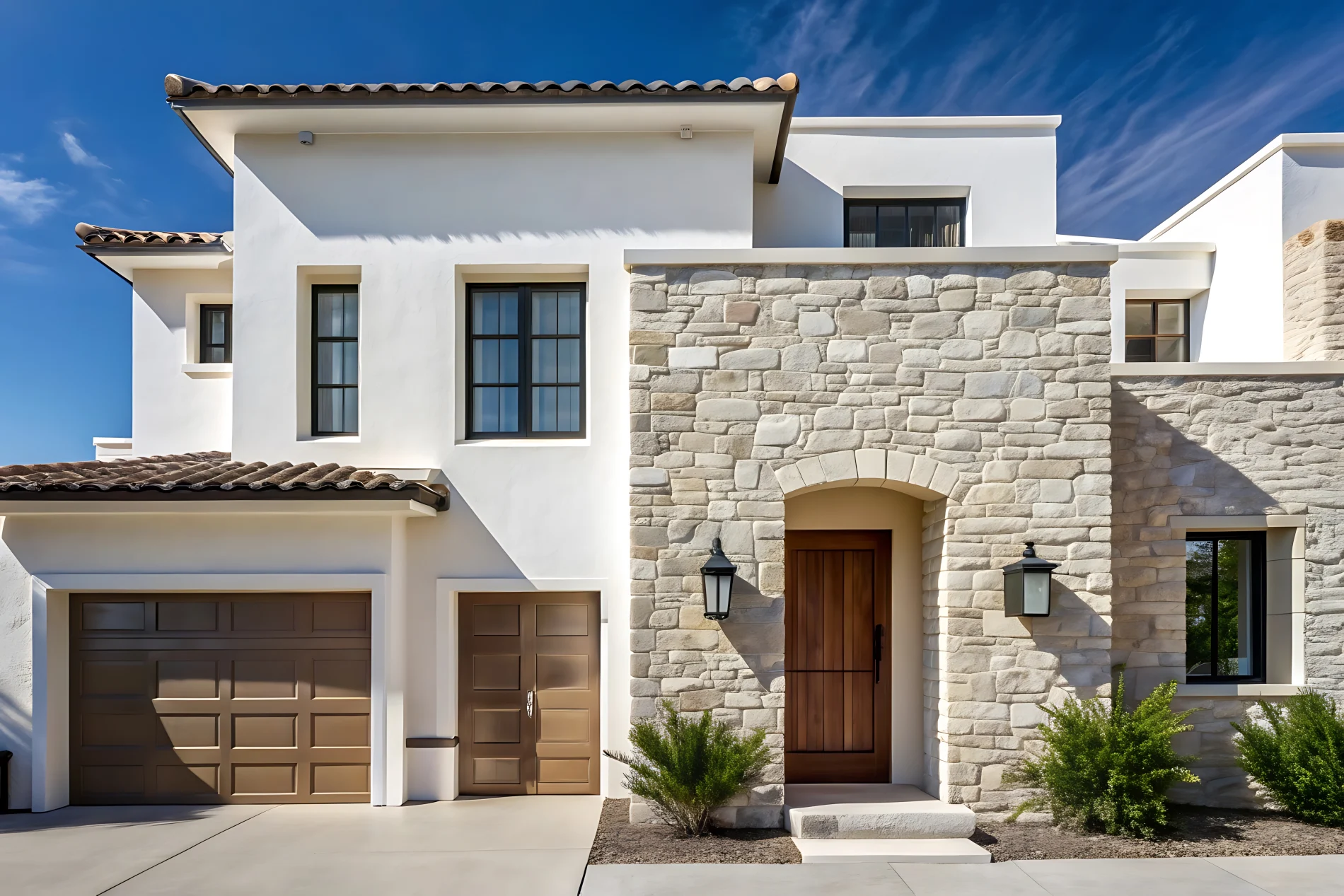 A two-story stucco house with a brown garage door, a wooden front door, white stucco, and stone over the entryway and the right side of the house.